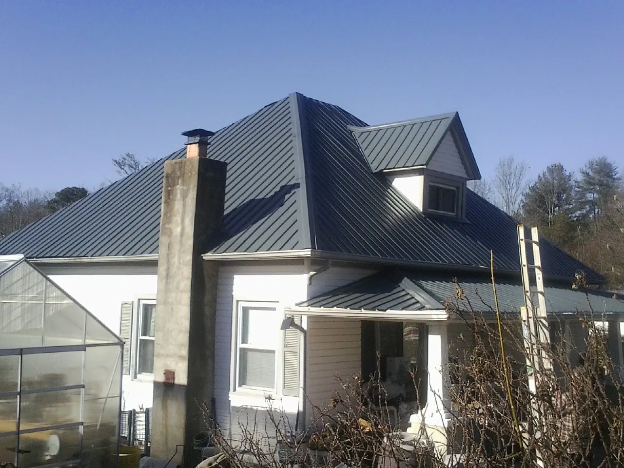 Dark blue standing seam metal roof on a white farmhouse with dormer — Slate & Tile Roof Repair by Roofing Brothers in Letts