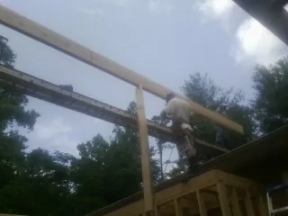 Carpenter setting a ridge beam over a new addition frame — Ice Dam Removal by Roofing Brothers in Letts