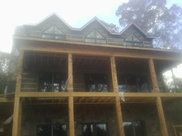 Dormers and porch framing on a large log home under construction — Roof Coating work by our crew in Letts