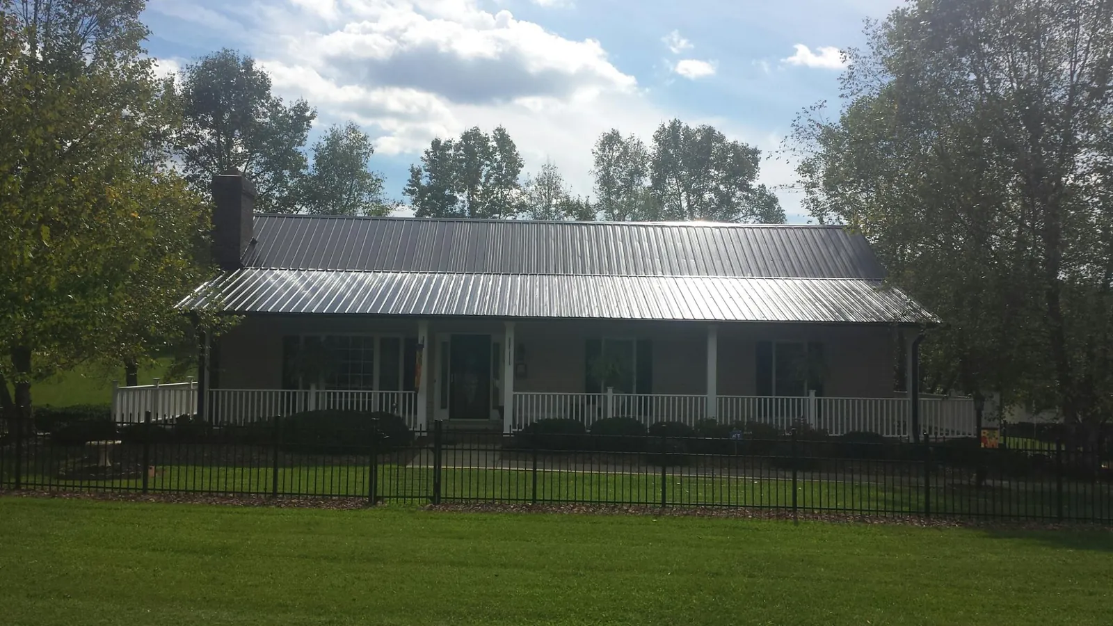 Gray metal roof on a brick ranch with a full width front porch — Gutter Guard Installation work by our crew in Letts