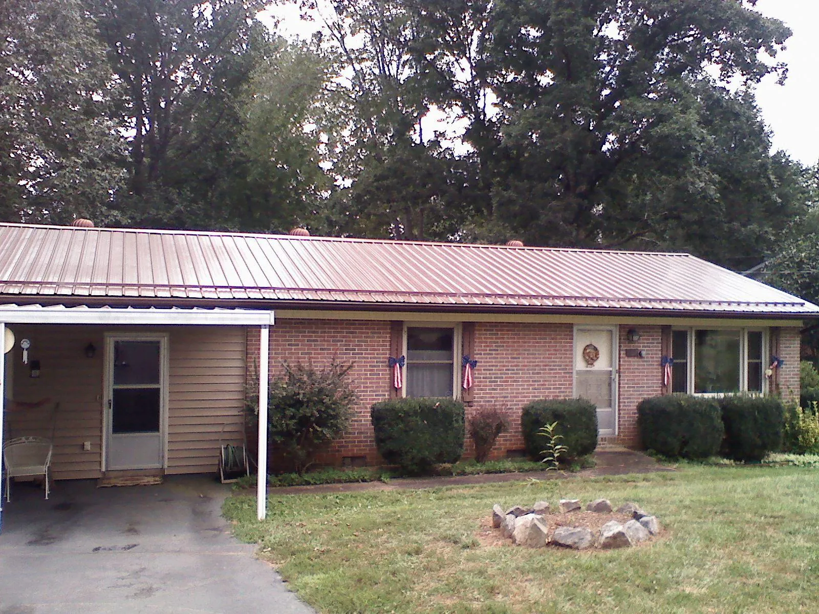 Bronze metal roof and carport on a brick ranch home — Roof Repair work by our crew in Letts