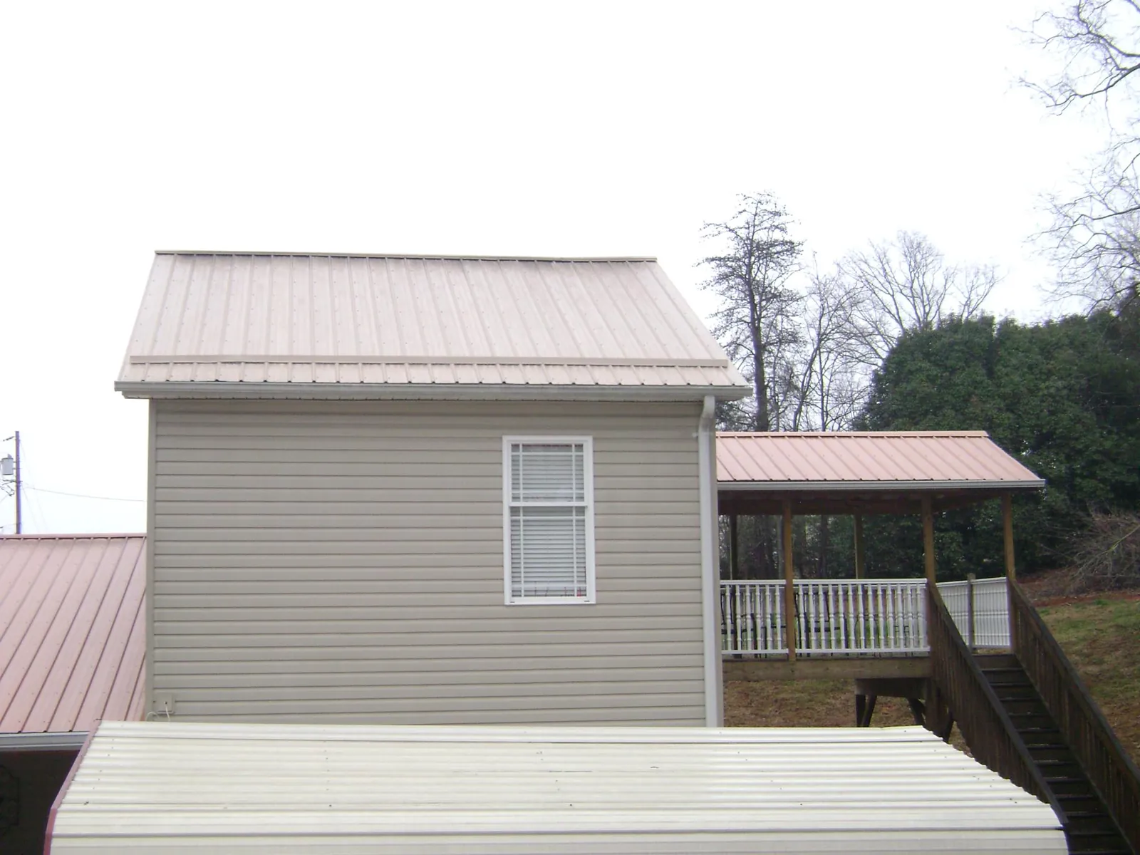 Tan metal roofs on a two story addition and attached porch, from a Roof Replacement job in Letts