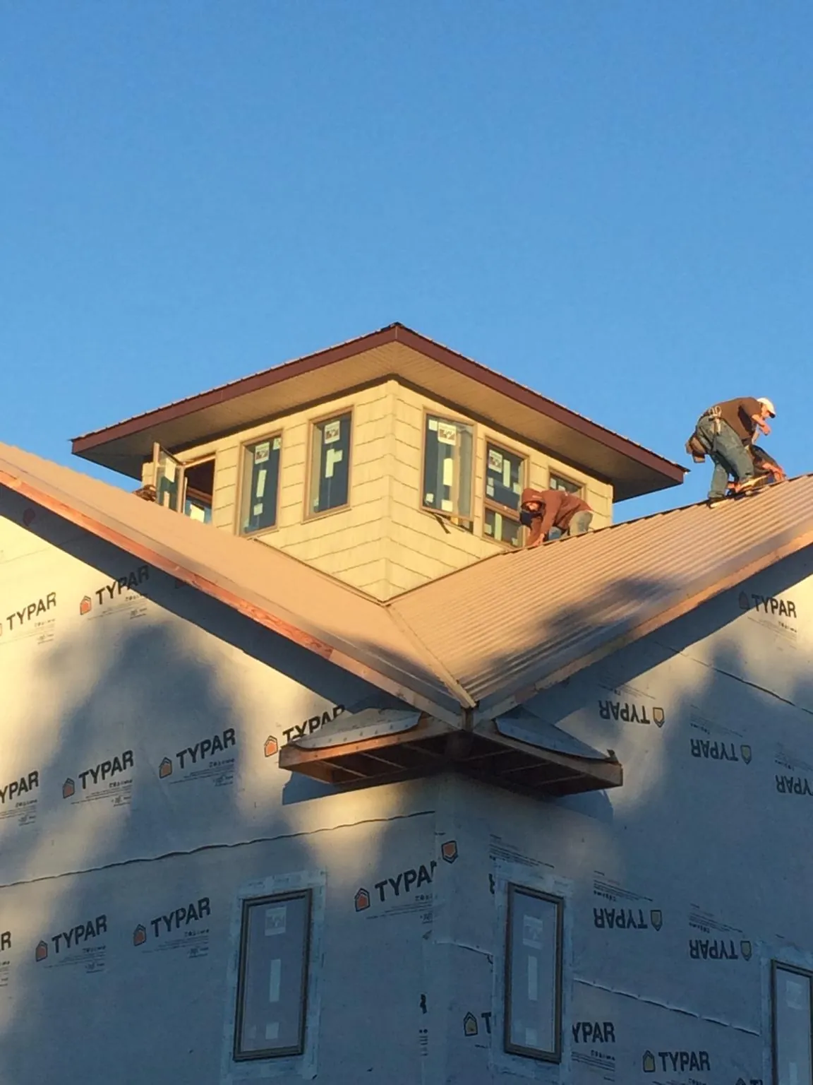 Roofers working around a rooftop cupola on a new metal roof at sunset — Roof Waterproofing in Letts by Roofing Brothers